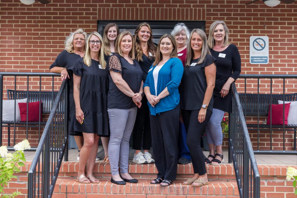 Nine administrators posing on stairs in front of Linley Park